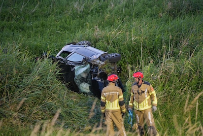 Jonge bestuurder rijdt van tien meter hoge dijk af en raakt zwaargewond, brandweer bevrijdt hem