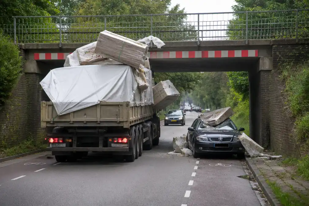 Vrachtwagen ramt spoorbrug in Holten, lading valt op auto